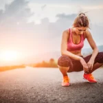 What Is the Carnivore Flu and How to Get Through It Fast . Exhausted woman resting after exercise on an empty road at sunset – symbolizing the fatigue and discomfort known as the "carnivore flu" during the first days of the diet.